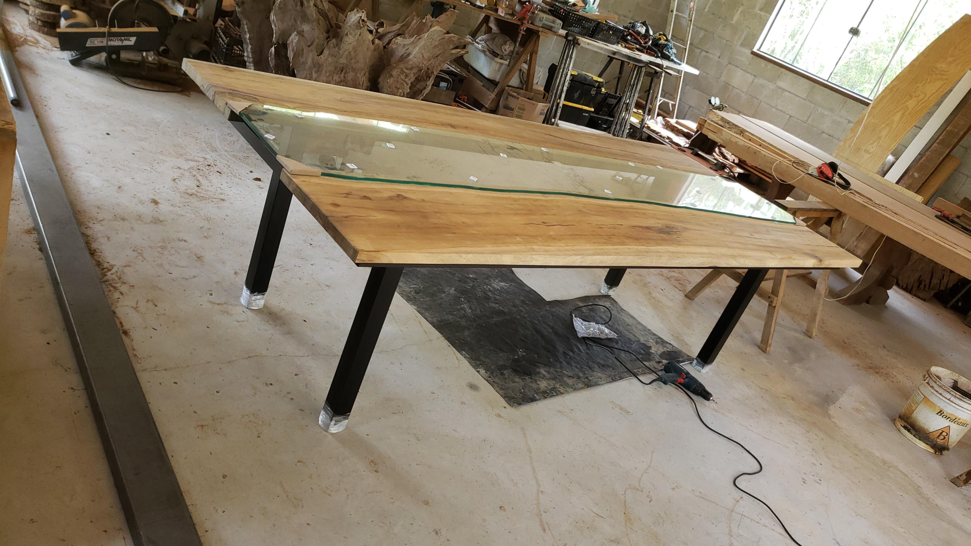 Mesa de madeira com faixa central de vidro na oficina