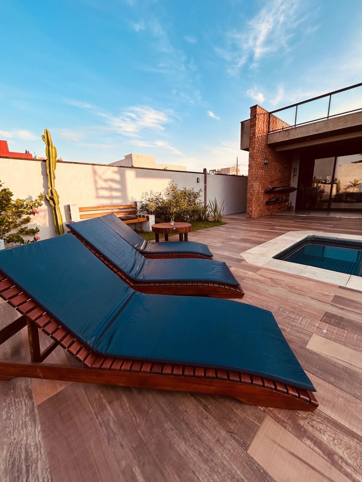 Espreguiçadeiras de madeira junto à piscina da Casa Alma de Surfista