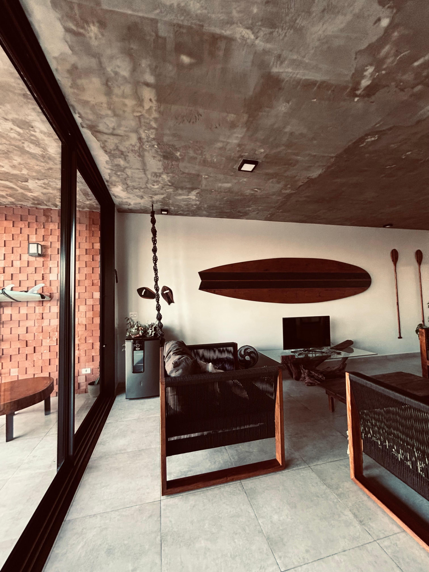 Sala da Casa Alma de Surfista com prancha de madeira e mobiliário artesanal