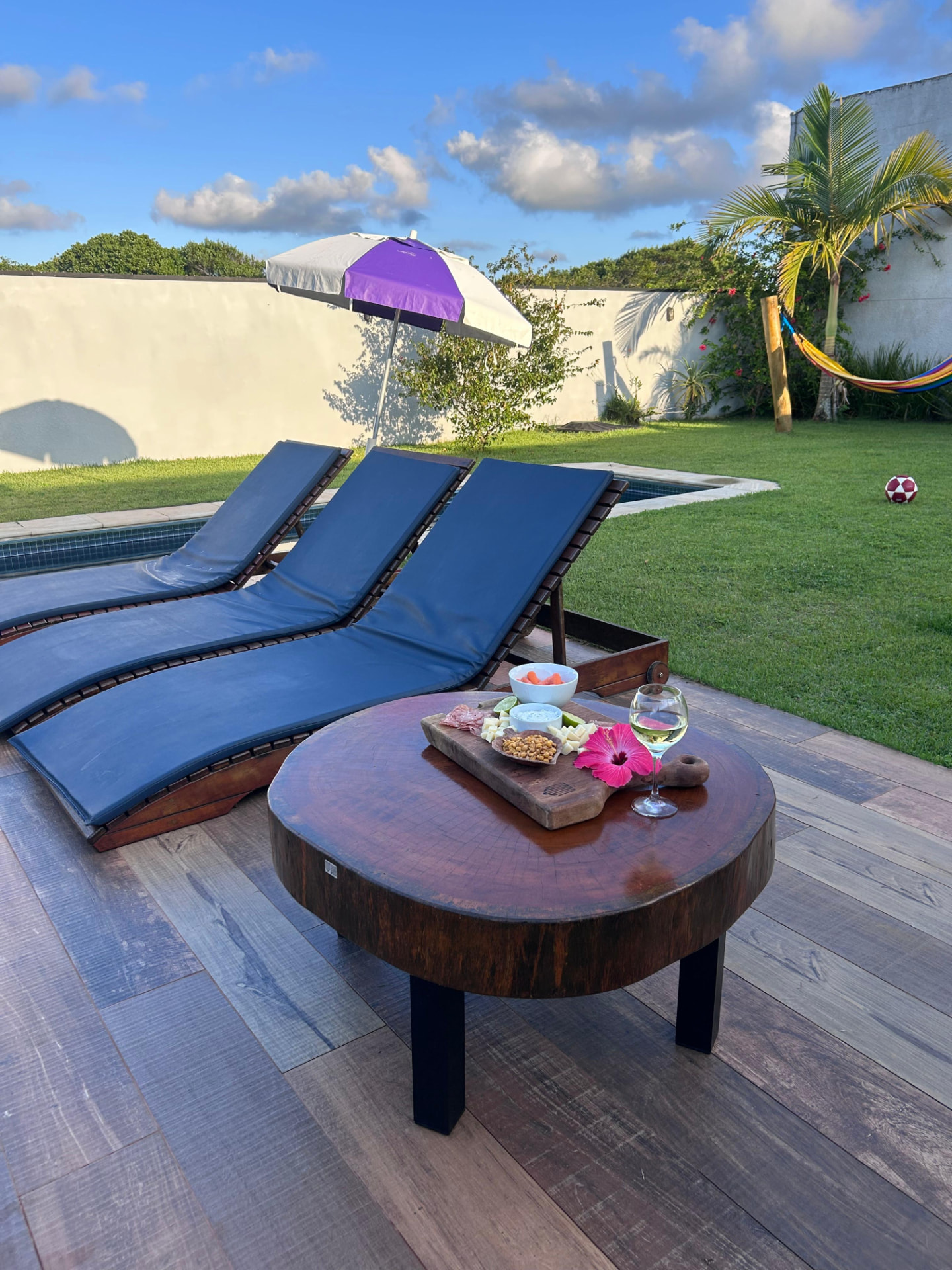 Mesa de centro redonda e espreguiçadeiras na área externa da Casa Alma de Surfista